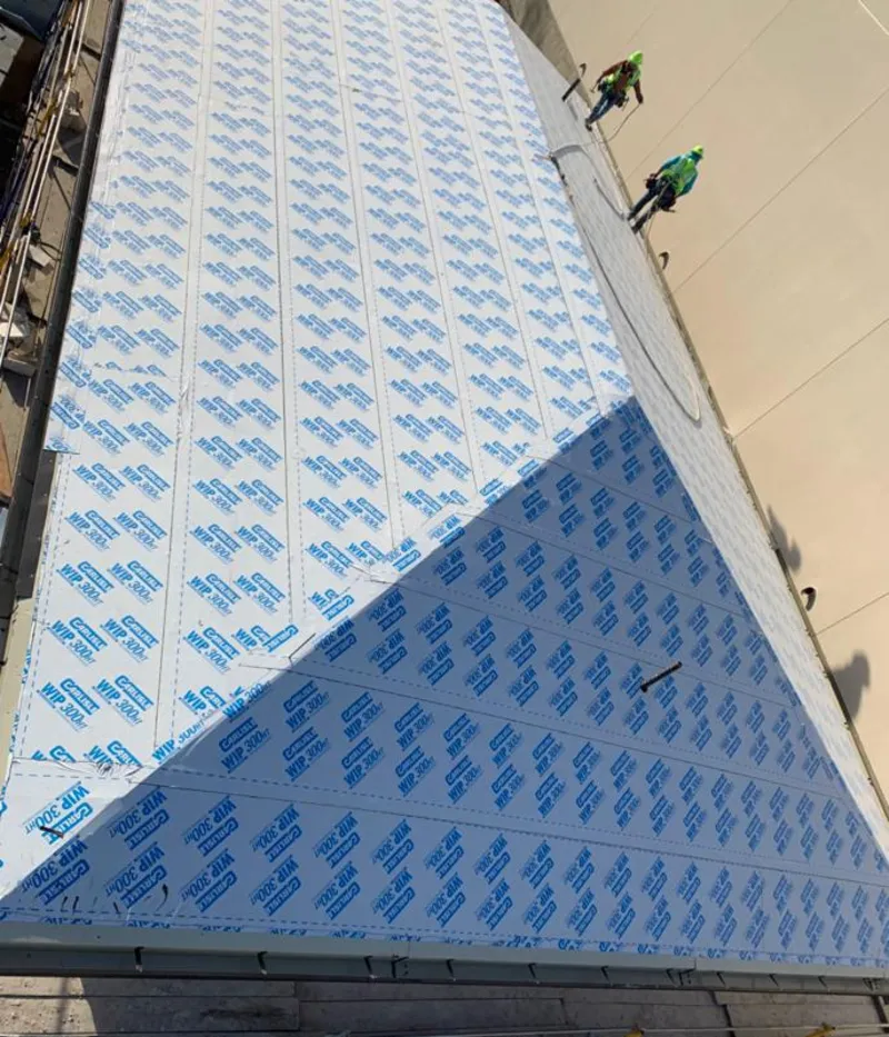 Professional roofers installing underlayment on a metal roof in Stowe